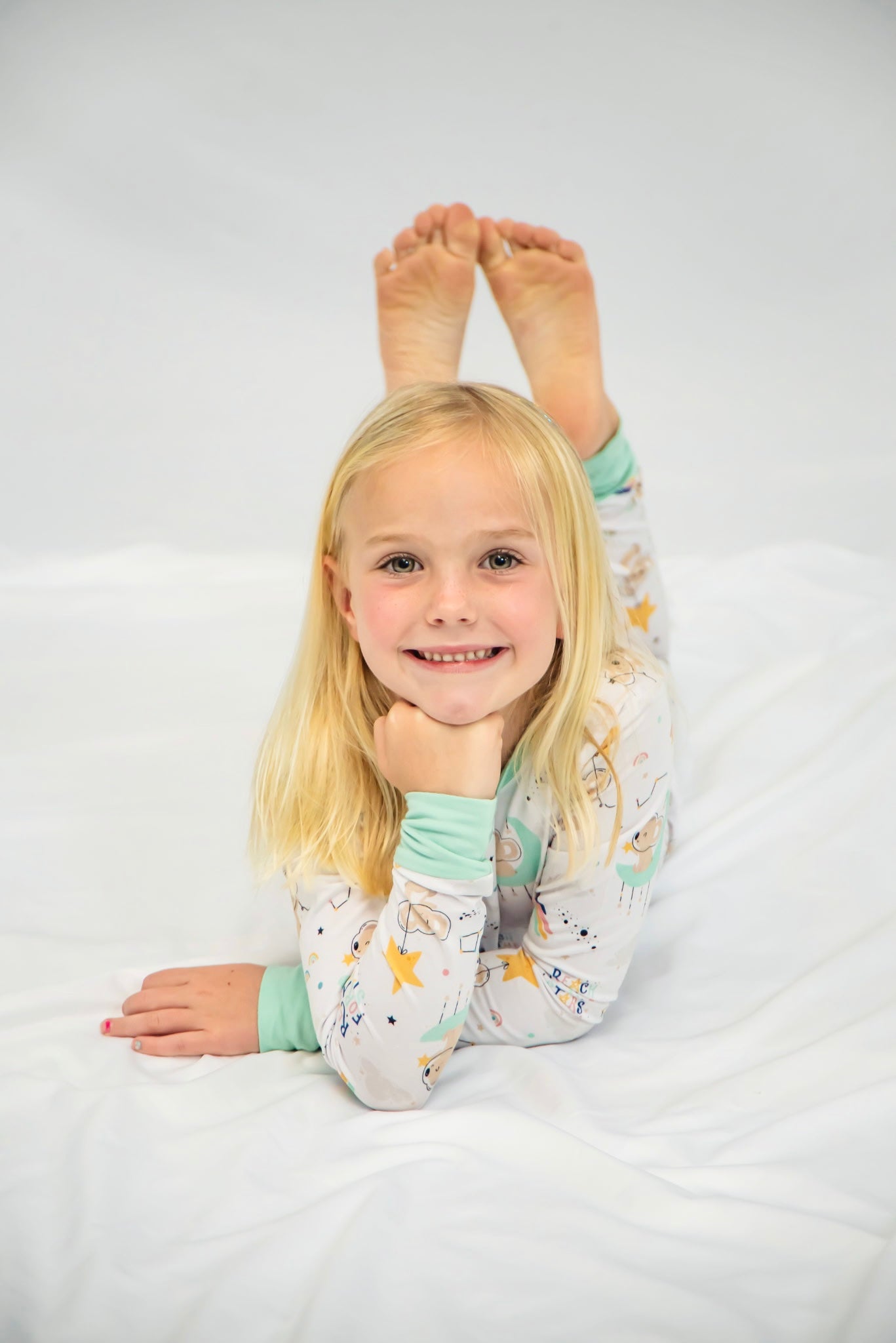 Child laying on the floor wearing a white Kenny Bamboo Pjs with Space theme