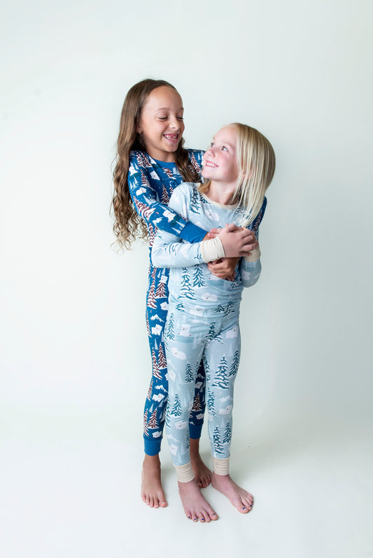 Two girls in a playful hug wearing Benny Gray and Benny Blue kids bamboo Pajamas